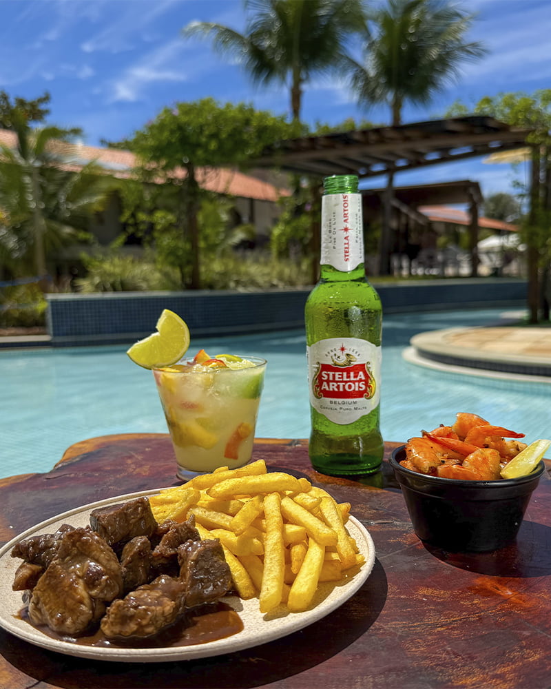 Drinks e petiscos no Salinas Maceió Resort All Inclusive Prato de carne com batata frita, camarão e drinks servidos à beira da piscina do Salinas Maceió.