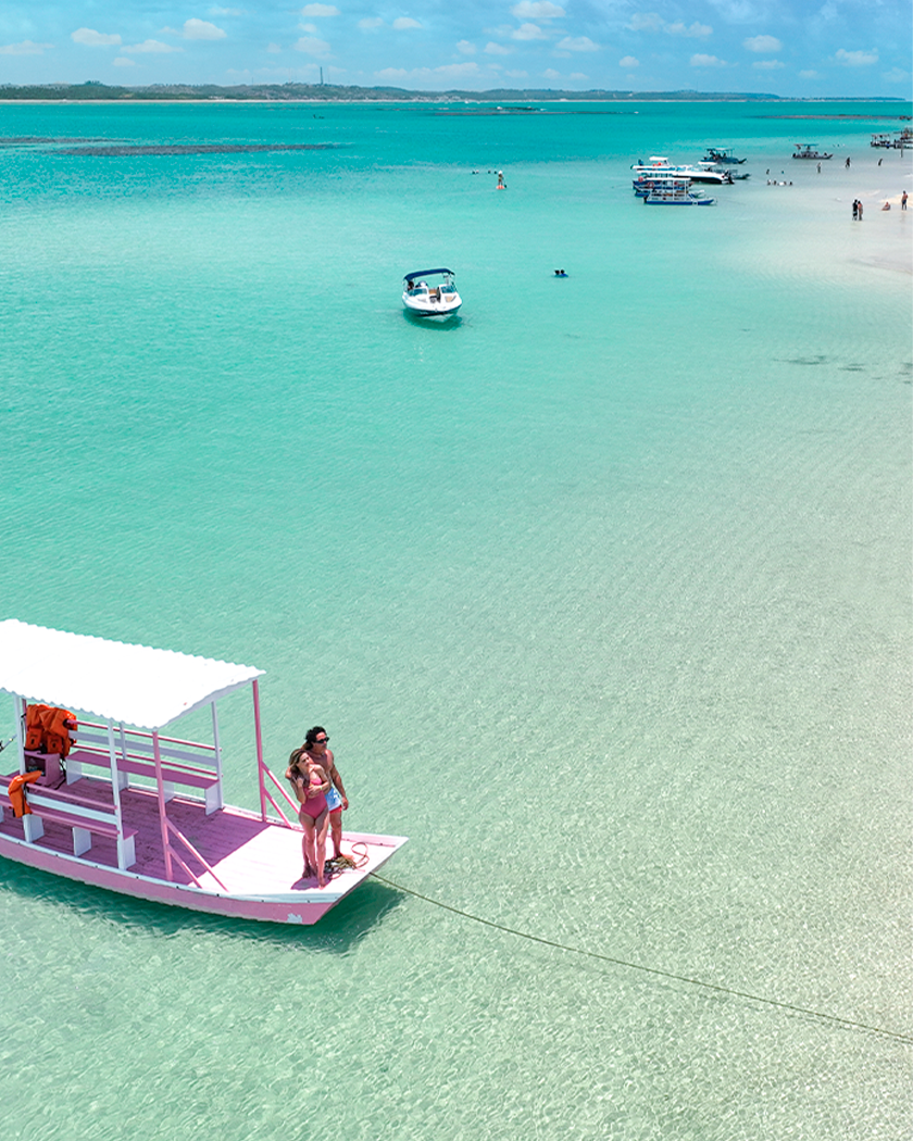 Passeio de catamarã em Japaratinga Passeio de jangada ancorada em águas cristalinas das piscinas naturais da praia de Japaratinga. Possível ver os recifes de corais e casal em cima da jangada rosa.