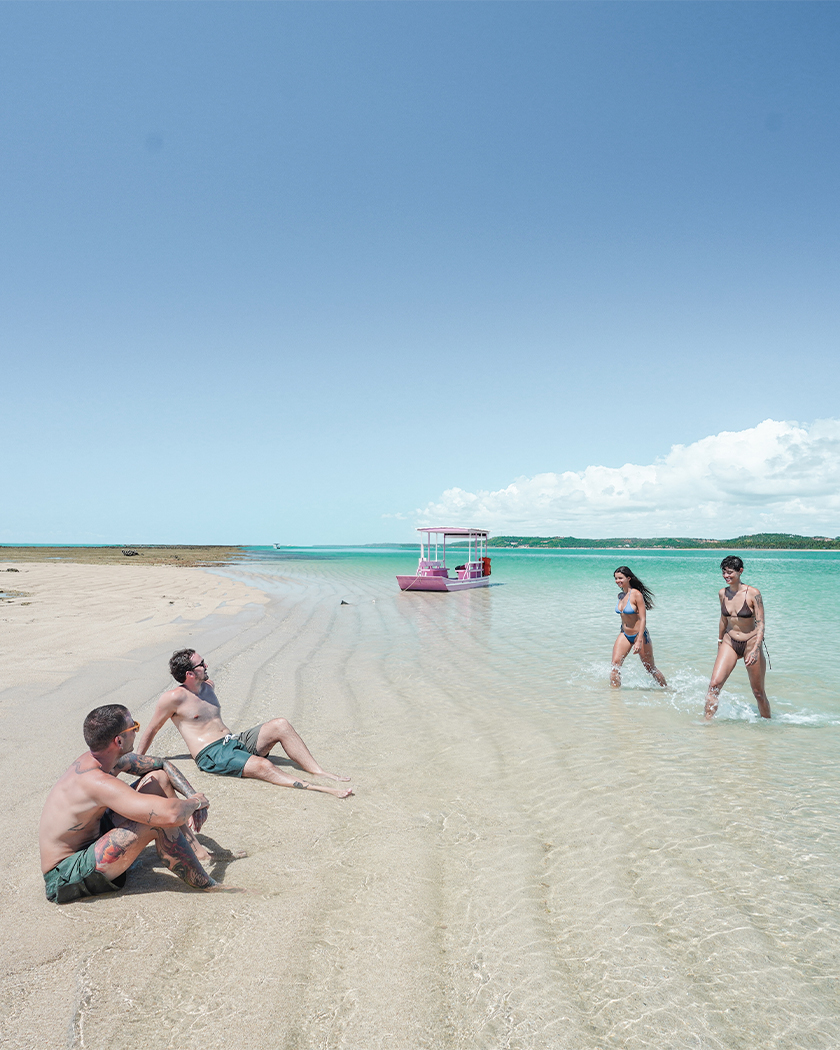 destinos paradisíacos Quatro amigos descansam ao lado de jangada na prainha da Croa de São Bento.
