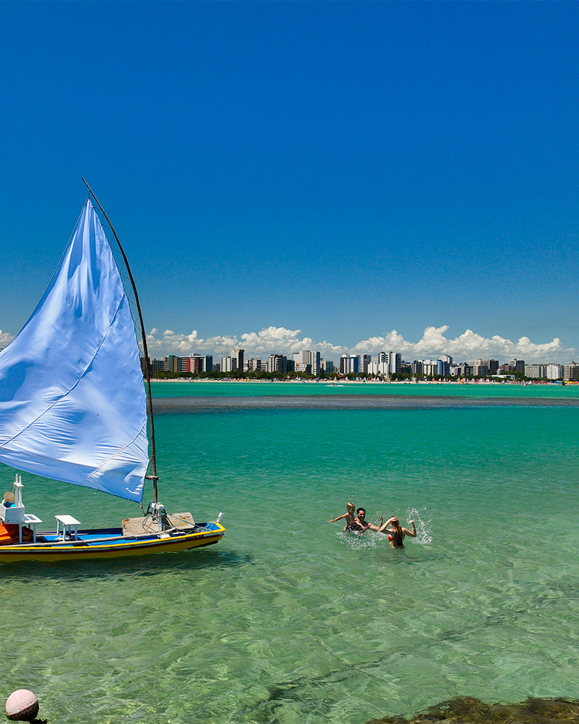 piscina natural pajuçara Vista aérea das piscinas naturais de Pajuçara, em Maceió. Com grandes formações de recifes de corais, cobertos com água azul turquesa, com presença de uma jangada e pessoas nadando.