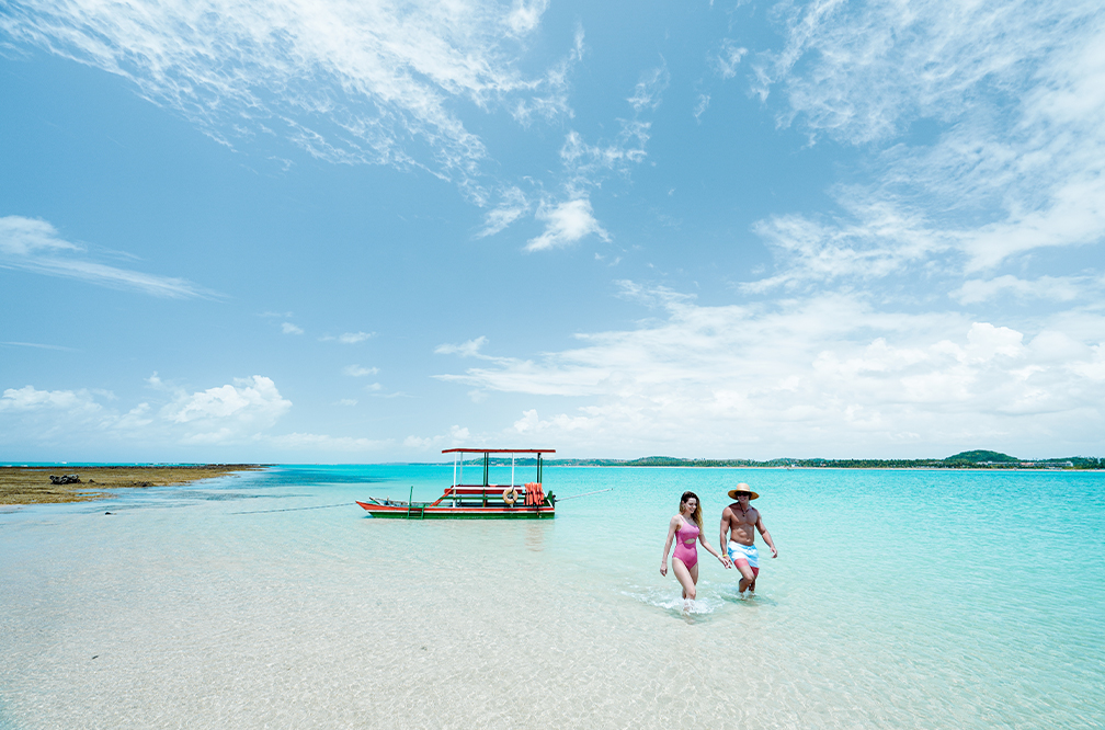 Destino paradisíaco na Croa de São Bento Vista aérea da Croa de São Bento , com bancos de areia, águas cristalinas azul-turquesa. Casal caminhando e um barco ancorado ao fundo