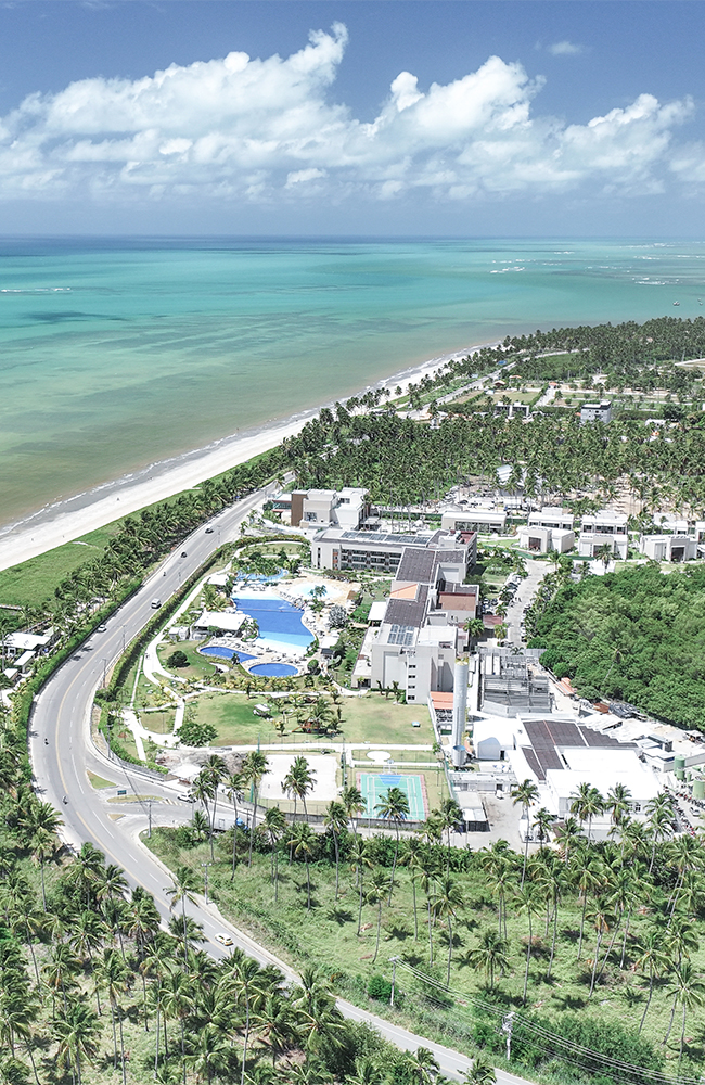 O paraíso conhecido como Japaratinga Lounge Resort Vista aérea do Japaratinga Lounge Resort, com suas acomodações, diversos pontos de consumo e complexo de piscinas, rodeado por uma densa vegetação nativa e à beira mar.
